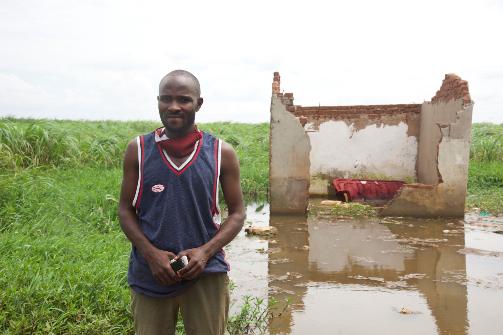Silus Musasizi stands in front of a destroyed building by Lake Victoria in Entebbe, Uganda on June 2, 2020. Thomson Reuters Foundation/Isaac Kasamani