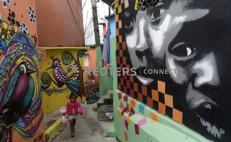 A girl walks along "Graffitti Way" at Prazeres slum in Rio de Janeiro March 24, 2014.  Sponsored by the French oil and gas company Total SA, about 50 houses were painted by graffiti artists all the way to the top of the community, local media said. REUTERS/Ricardo Moraes (BRAZIL - Tags: SOCIETY) - GM1EA3P02IO01