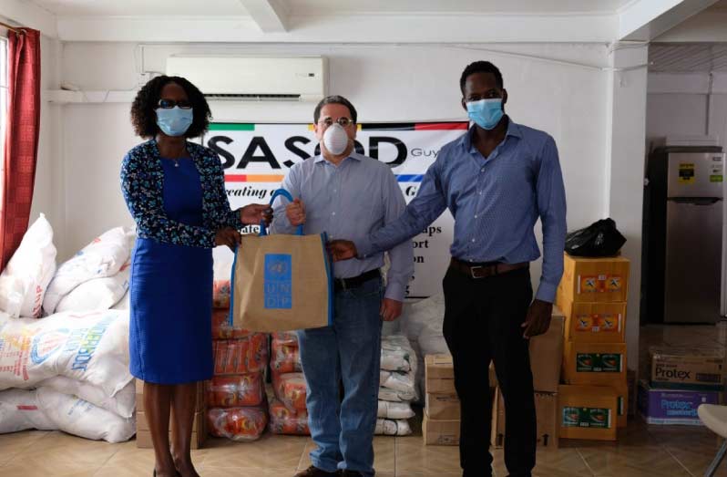 Mr. Jairo Valverde, UNDP’s Resident Representative, hands over food items to Dr. Rhonda Moore, Director of the National AIDS Programme Secretariat and Mr. Joel Simpson, Managing Director of SASOD