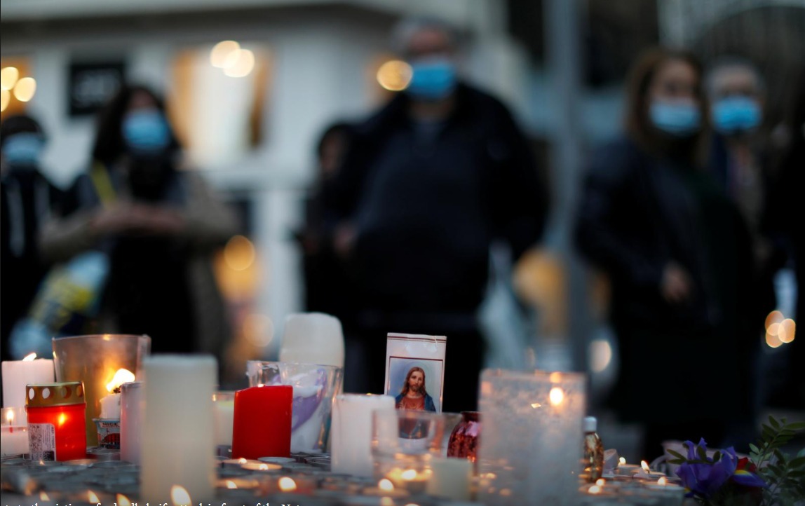 People gather near candles and flowers to pay tribute to the victims of a deadly knife attack in front of the Notre Dame church in Nice, France, October 30, 2020. REUTERS/Eric Gaillard