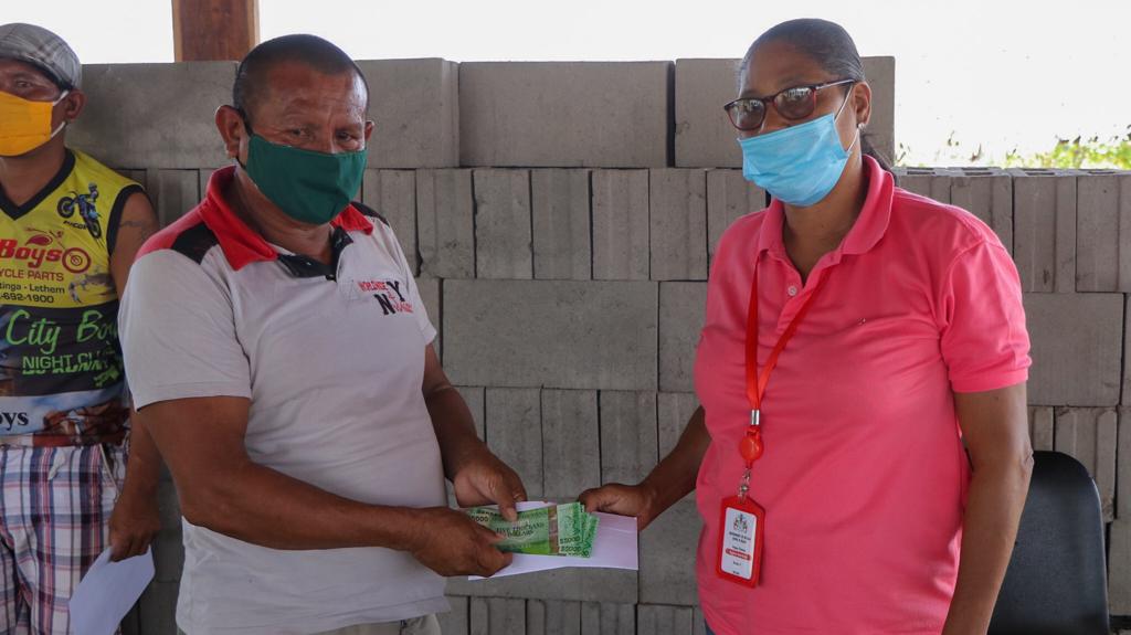 A Region Nine resident receives his cash grant from an official