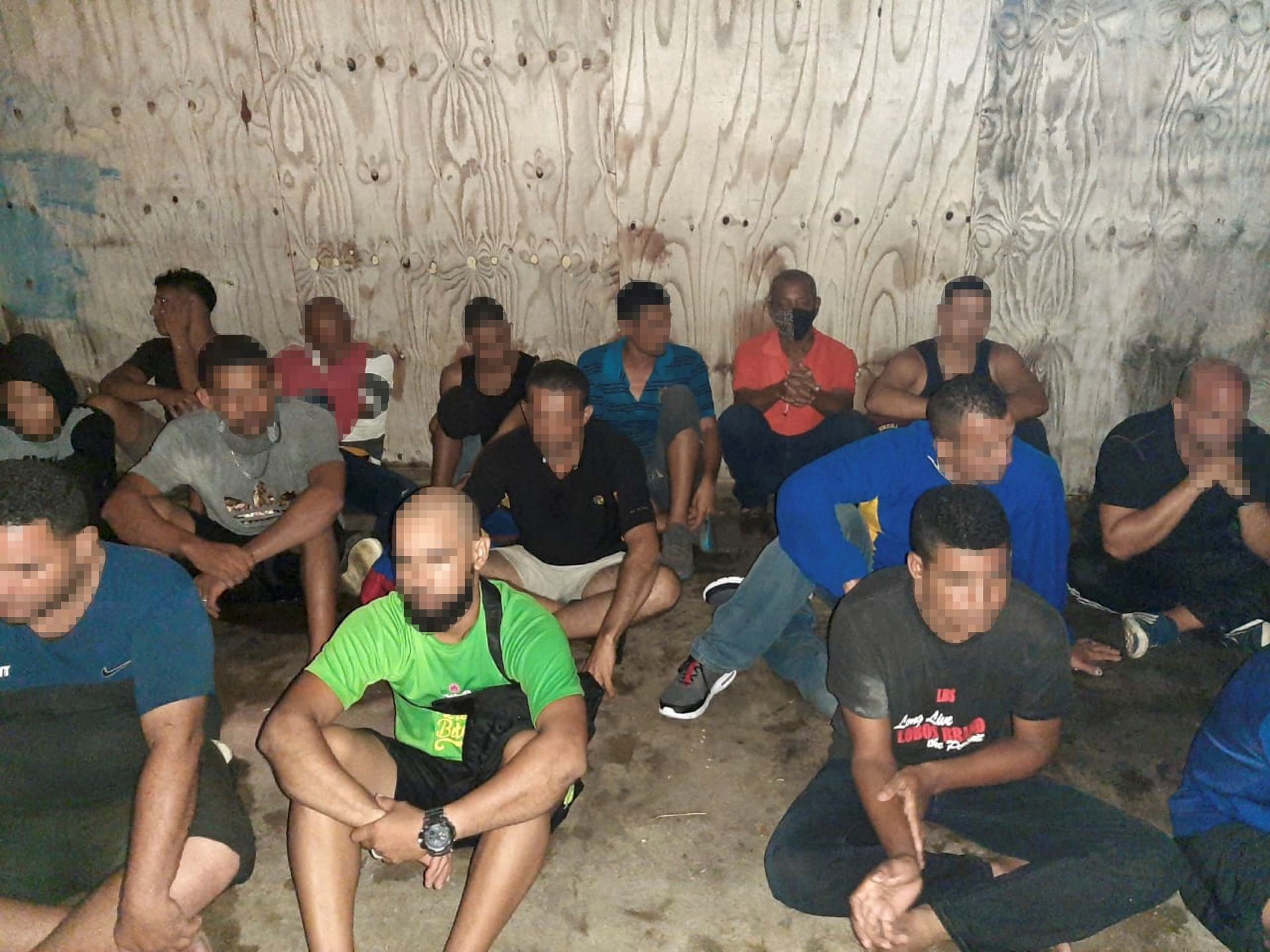Some of the Venezuelan migrants arrested on July 16 by T&T Coast Guard sit outside the Cedros Security Complex. (Trinidad and Tobago Guardian)