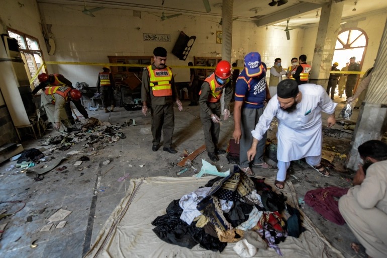 Rescue workers collect the remains of victims after a blast at a religious school in Peshawar [Abdul Majeed/AFP]