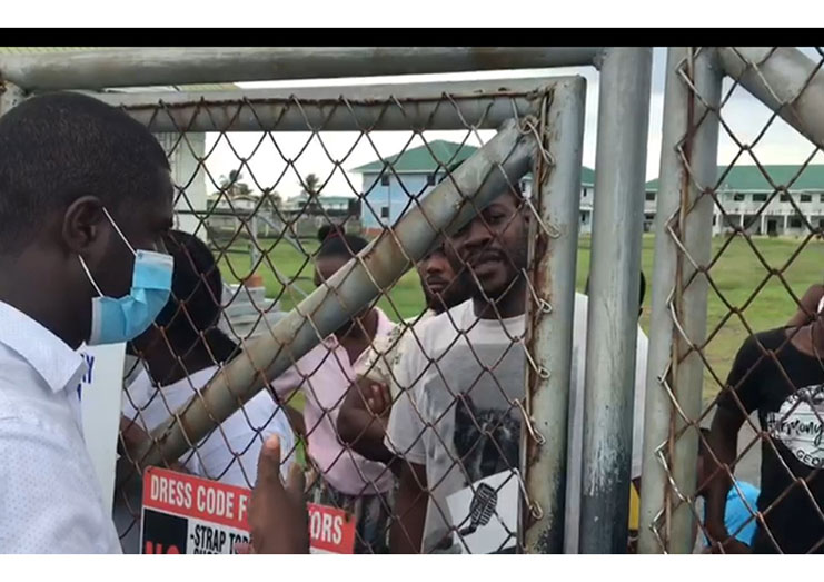 Attorney-at-Law Darren Wade speaking to some of the detained Haitians through a barbed wire fence before he was provided access to the Hugo Chavez Centre for Rehabilitation and Reintegration.