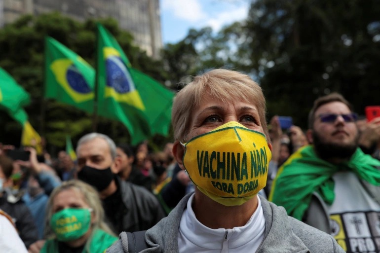 A demonstrator wearing a face mask reading ‘No Vaccine. Doria out’ protests against Sao Paulo governor Joao Doria and China’s Sinovac vaccine [File: Amanda Perobelli/Reuters]