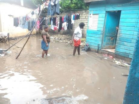 Residents plod through floodwaters in a yard situated on of Olympic Way, St Andrew, on Sunday. As heavy rainfall associated with Tropical Storm Eta triggered landslides and flooding across Jamaica, the Meteorological Service announced a flash flood warning for today. 
Photo by Jason Cross