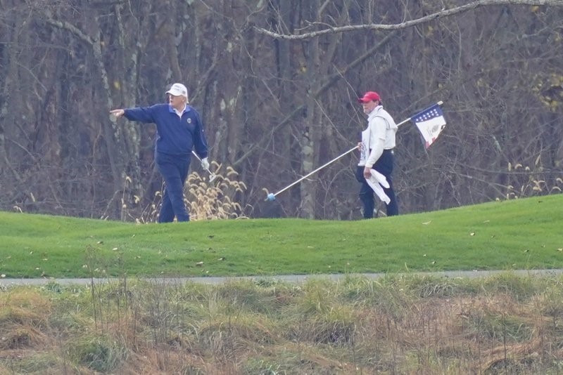 President Donald Trump, left, gesturing while playing golf at Trump National Golf Club in Sterling, Va., as seen from the other side of the Potomac River in Darnestown, Md., Sunday, Nov. 15, 2020. (AP Photo/Manuel Balce Ceneta)