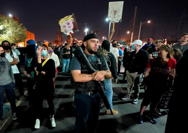 Trump supporters rally outside the Maricopa County vote-counting office in Phoenix as two counterprotesters stand in the rear [Matt York/AP]