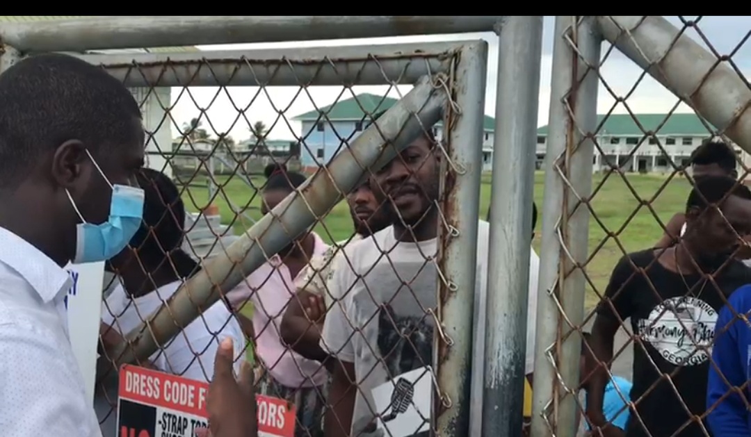 Attorney-at-Law Darren Wade speaking to some of the detained Haitians through a barbed wire fence before he was provided access to the Hugo Chavez Centre for Rehabilitation and Reintegration last week Sunday