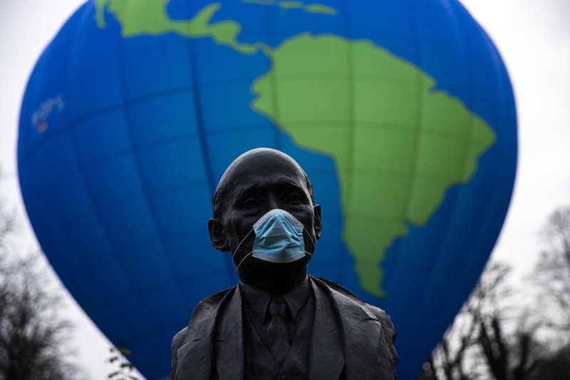 The bust of French statesman Robert Schuman, one of the founders of the European Union, is seen while environmental activists launch a hot air balloon during a demonstration outside of an EU summit in Brussels, Thursday, Dec. 10, 2020. (AP Photo/Francisco Seco)