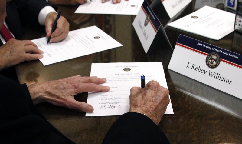 FILE - In this Dec. 19, 2016, file photo members of the Mississippi Electoral College sign certificates of vote in the process of formally casting their electoral votes in the 2016 General Election for President and Vice President of the United States at the Capitol in Jackson, Miss. Presidential electors are meeting across the United States Monday, Dec. 14, 2020, to formally choose Joe Biden as the nation's next president. (AP Photo/Rogelio V. Solis, File)