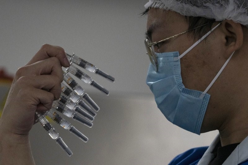 A worker inspects syringes of a vaccine for COVID-19 produced by Sinovac at its factory in Beijing on Thursday, Sept. 24, 2020. (AP Photo/Ng Han Guan)