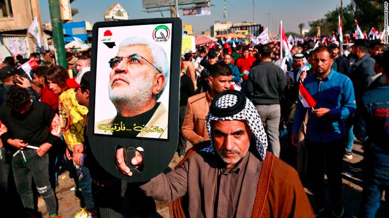 A supporter of Abu Mahdi al-Muhandis, deputy commander of the Popular Mobilization Forces, holds a photo of him during a protest in Tahrir Square, Baghdad, Iraq, Sunday, Jan. 3, 2021.
