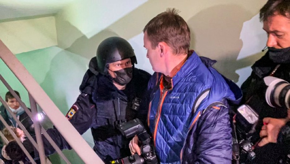 A police officer pushes photographers from a door of the apartment where Oleg Navalny, brother of jailed opposition leader Alexei Navalny lives in Moscow, Russia, Wednesday, Jan. 27, 2021. Police are searching the Moscow apartment of jailed Russian opposition leader Alexei Navalny, another apartment where his wife is living and two offices of his anti-corruption organization. Navalny's aides reported the Wednesday raids on social media. (AP Photo/Mstyslav Chernov)
