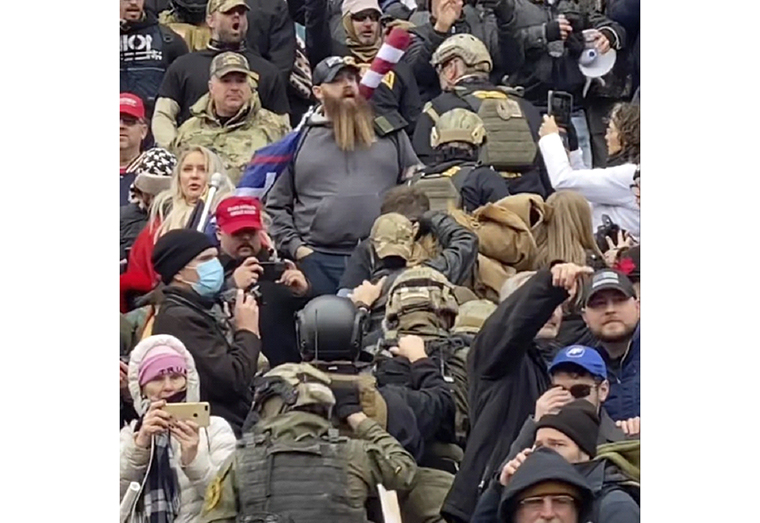 In this Jan. 6, 2021 image from video provided by Robyn Stevens Brody, a line of men wearing helmets and olive drab body armor walk up the marble stairs outside the U.S. Capitol in Washington in an orderly single-file line, each man holding the jacket collar of the man ahead. The formation, known as "Ranger File," is standard operating procedure for a combat team "stacking up" to breach a building. (Robyn Stevens Brody via AP)
