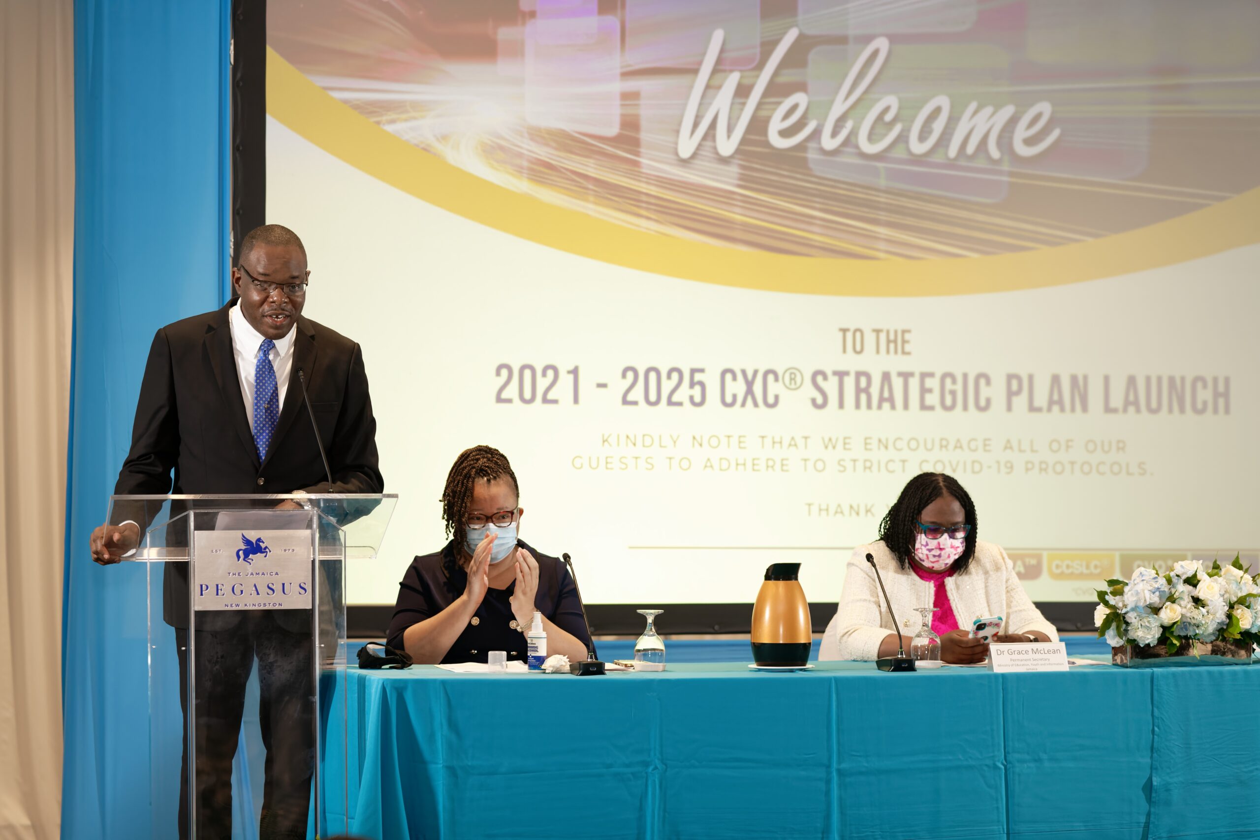 Dr Wayne Wesley, Registrar and CEO of CXC® addressing the audience, beside Master of Ceremonies. Ms Jodine Williams, Senior Manager - Syllabus & Curriculum Development Unit, CXC