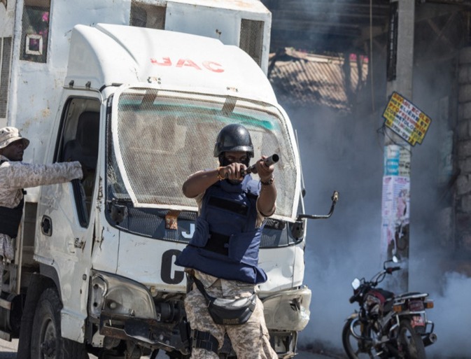 A police officer shoots tear gas towards a group of journalists gathered to cover a protest against the Haitian president, in Port-au-Prince on Wednesday [Valerie Baeriswyl/AFP]