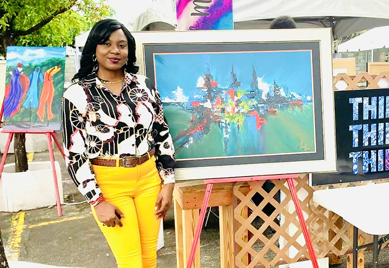 : Guyanese artist Oleisa Scott stands next to her artwork during an exhibition in the Twin-island Republic.