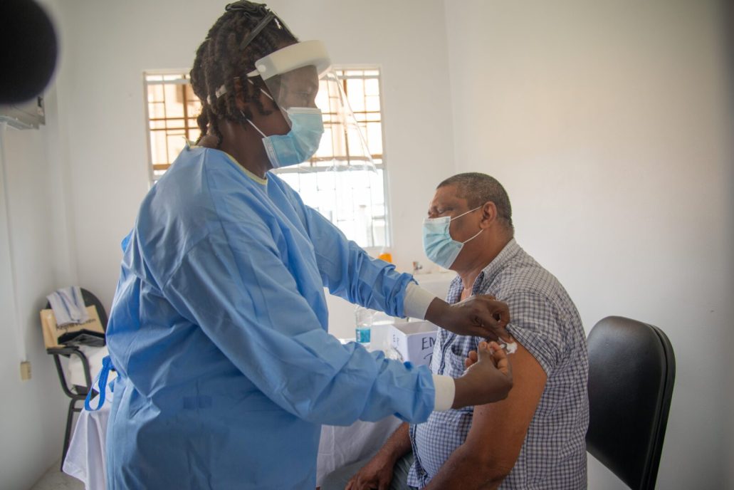Nurse Dawnette Payne administers the COVID-19 vaccine to Region Three residents Mr. Kaishudat Deowkslia and Bibi Nafeesa Shariff