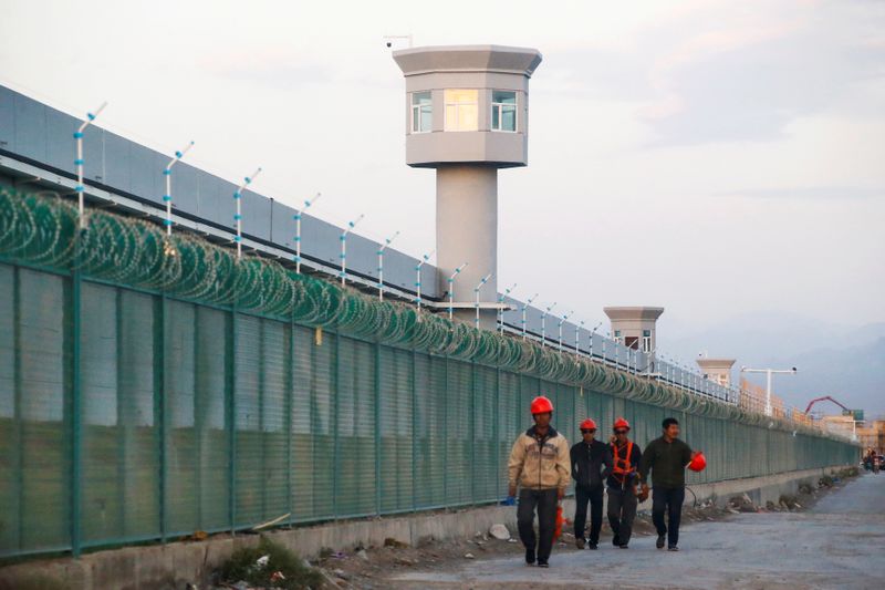 FILE PHOTO: Workers walk by the perimeter fence of what is officially known as a vocational skills education centre in Dabancheng in Xinjiang Uighur Autonomous Region, China September 4, 2018. Picture taken September 4, 2018. REUTERS/Thomas Peter