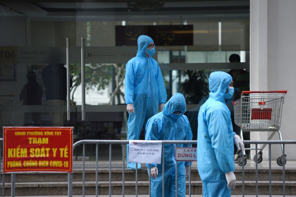 Medical workers in protective suits stand outside a quarantined building amid the coronavirus disease (COVID-19) outbreak in Hanoi, Vietnam, January 29, 2021. REUTERS/Thanh Hue
