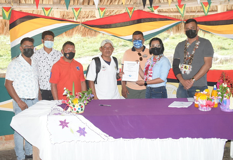 Minister Rodrigues handing over contract to Toshao of Monkey Mountain surrounded by Ministry of Housing and GWI officials