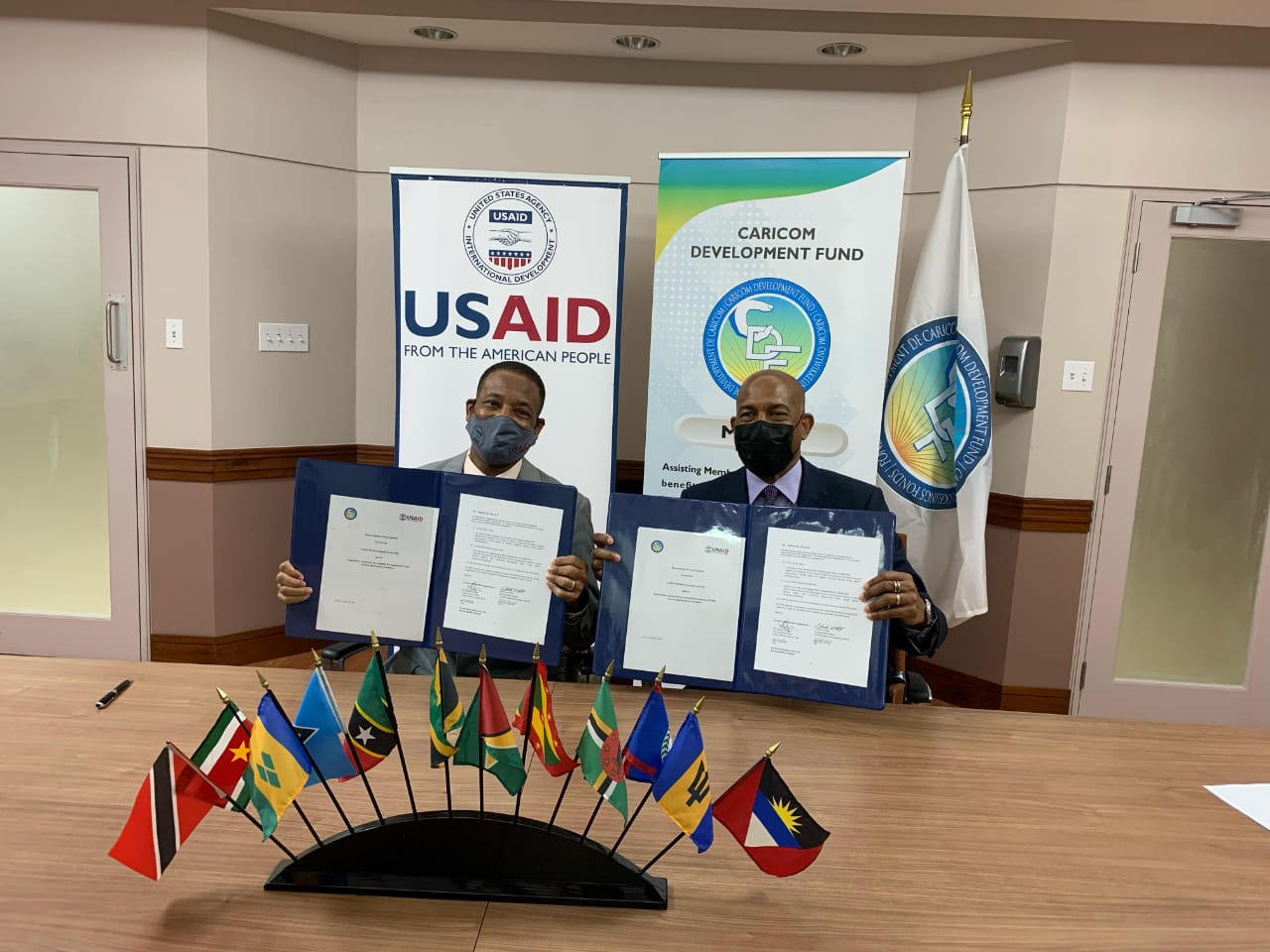 Regional Representative, USAID/ESC, Clinton White (left) and CEO, CDF, Rodinald Soomer show signed copies of the MOU which provides a broad framework for cooperation between the two entities.