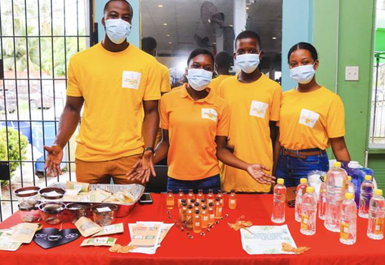 Moore’s Fiancé, Daniel Anthony; Owner of Miracle Oils, Tatyana Moore, along with her brother and sister displaying her products at and exhibition (from left to right)