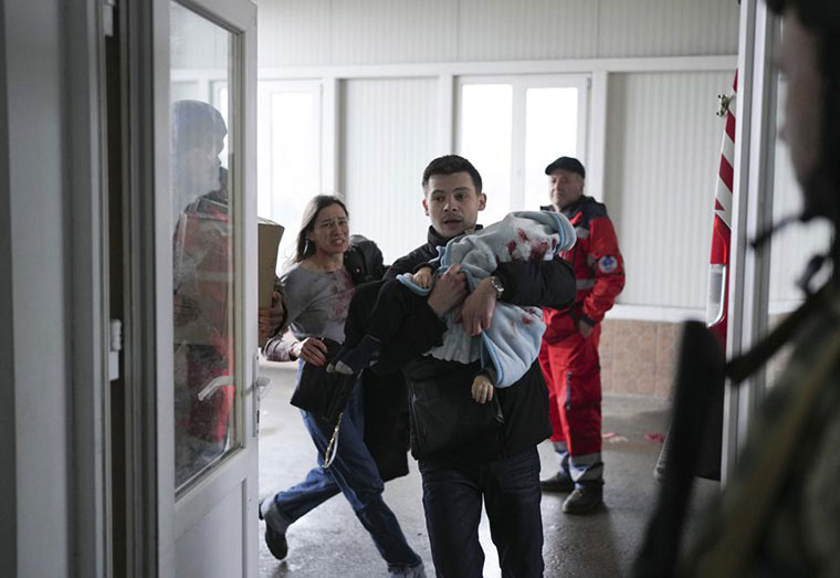 Marina Yatsko, left, runs behind her boyfriend Fedor carrying her 18 month-old son Kirill who was killed in shelling, as they arrive at a hospital in Mariupol, Ukraine, Friday, March 4, 2022. (AP Photo/Evgeniy Maloletka)