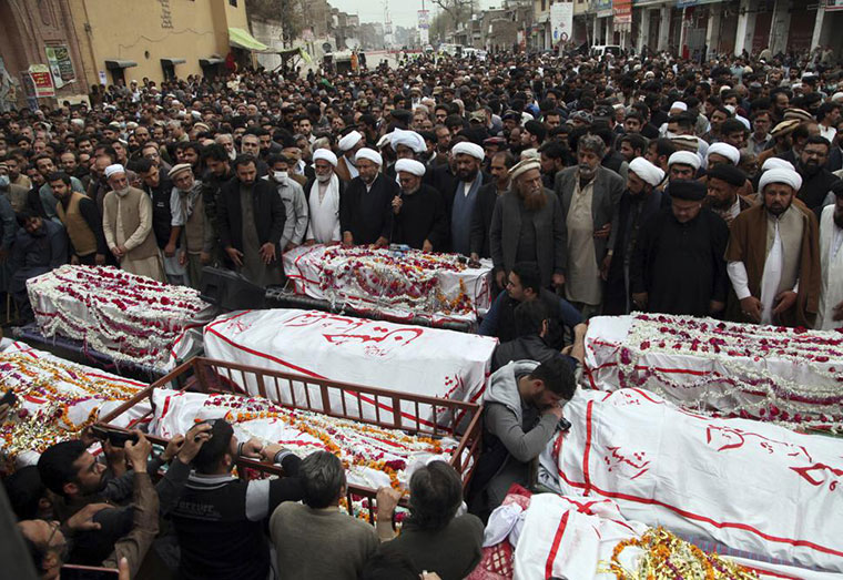 People attend the funeral prayers for the victims of Friday's suicide bombing in Peshawar, Pakistan, Saturday, March 5, 2022. The Islamic State says a lone Afghan suicide bomber struck inside a Shiite Muslim mosque in Pakistan's northwestern city of Peshawar during Friday prayers, killing dozens worshippers and wounding more than 190 people. (AP Photo/Muhammas Sajjad)