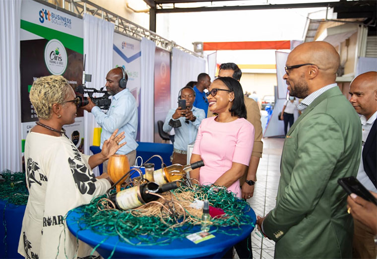 Minister of Tourism, Industry and Commerce, Oneidge Walrond, and COO GTT Business Solutions, Orson Ferguson, interact with an exhibitor at the Business Expo