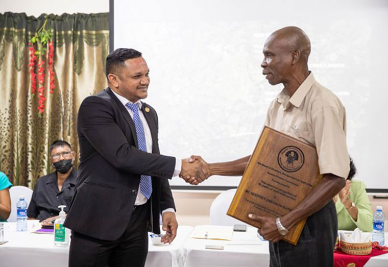 Technical Advisor on Forestry, Godfrey Marshall receiving a plaque from Minister of Natural Resources, Vickram Bharrat for his longstanding service