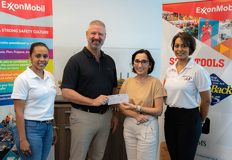 ExxonMobil Guyana’s Safety Manager Brad Edlington hands over the cheque to UWSC President Jennifer Prashad with other members of the organisation in attendance.