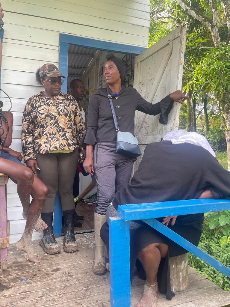 Former Minister, Simona Broomes looks on as Tracey Flue, the mother of the three victims, is consoled by her mother