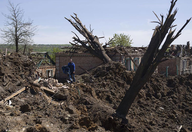 People stand in destroyed residential area after Russian airstrike in Bakhmut, Donetsk region, Ukraine, Saturday, May 7, 2022. (AP Photo/Evgeniy Maloletka)