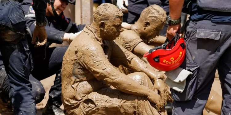 Volunteer rescuers, completely covered in mud, receive medical treatment after being attacked by wasps while removing debris (Reuters Photo)