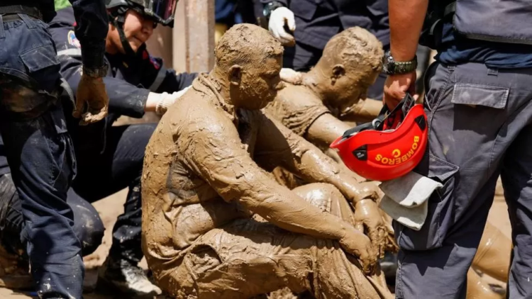 Volunteer rescuers, completely covered in mud, receive medical treatment after being attacked by wasps while removing debris (Reuters Photo)
