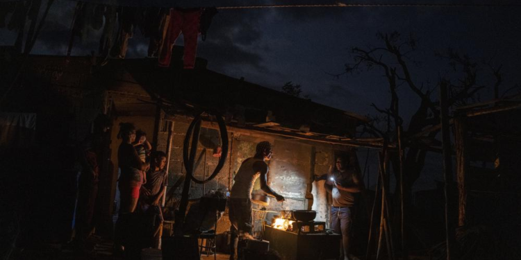 The Ramos family cooks dinner over a fire outside their storm-damaged home a week after Hurricane Ian knocked out electricity to the entire island, in La Coloma, Pinar del Rio province,