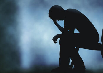 Editable vector silhouette of a man sitting with his head in his hand with background made using a gradient mesh