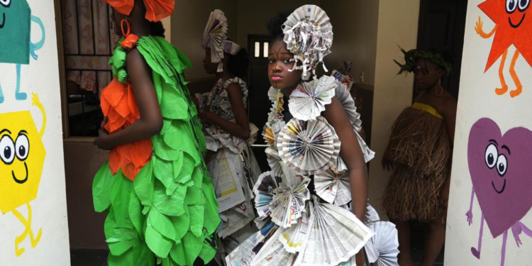 Jalokun Nifemi, wearing an outfit made from recycled newspapers, waits back stage before a 'trashion show' in Sangotedo Lagos, Nigeria, Saturday, Nov. 19, 2022. (AP Photo/Sunday Alamba)