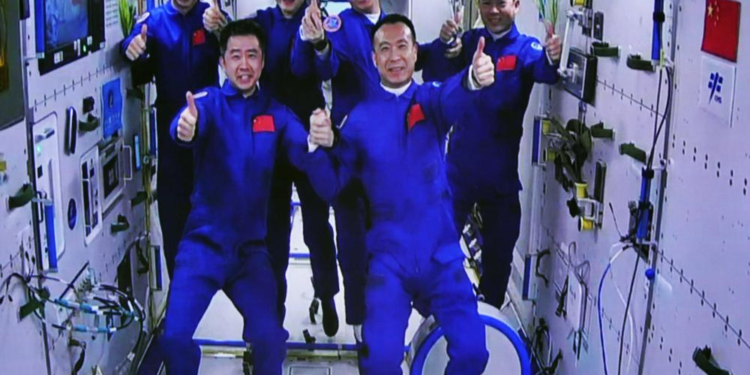 In this photo released by Xinhua News Agency, an image captured off a screen at the Jiuquan Satellite Launch Center in northwest China shows the Shenzhou-15 and Shenzhou-14 crew taking a group picture with their thumbs up after a historic gathering in space on Wednesday, Nov. 30, 2022. Three Chinese astronauts docked early Wednesday with their country's space station, where they will overlap for several days with the three-member crew already onboard and expand the facility to its maximum size. (Guo Zhongzheng/Xinhua via AP)