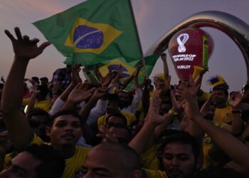Fans cheer and wave Brazilian flags in front of the World Cup countdown clock in Doha, Qatar, Friday, Nov. 18, 2022. Fans poured into Qatar on Friday ahead of the Middle East's first World Cup as Doha ordered beers not to be poured out at stadiums during the tournament — a last-minute surprise largely welcomed by the country's conservative Muslims and shrugged off by giddy fans. (AP Photo/Jon Gambrell)