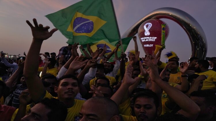 Fans cheer and wave Brazilian flags in front of the World Cup countdown clock in Doha, Qatar, Friday, Nov. 18, 2022. Fans poured into Qatar on Friday ahead of the Middle East's first World Cup as Doha ordered beers not to be poured out at stadiums during the tournament — a last-minute surprise largely welcomed by the country's conservative Muslims and shrugged off by giddy fans. (AP Photo/Jon Gambrell)