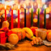 Kwanzaa holiday concept with decorate seven candles red, black and green, gift box, pumpkin, bowl and fruit on light blur bokeh background