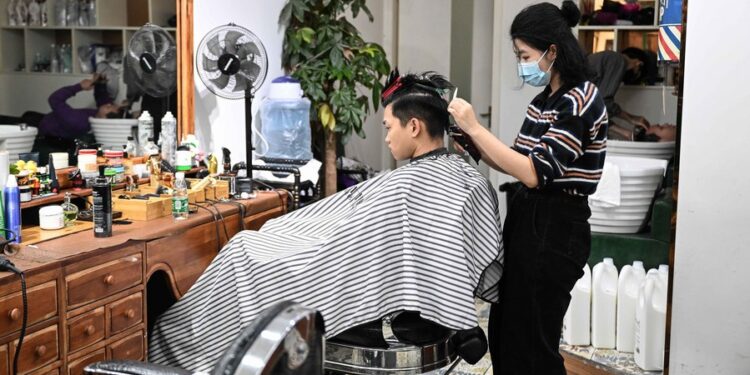 A hairdresser cuts a customer's hair at a hair salon in Liwan District of Guangzhou, capital of south China's Guangdong Province, Dec. 1, 2022. (Xinhua/Deng Hua)