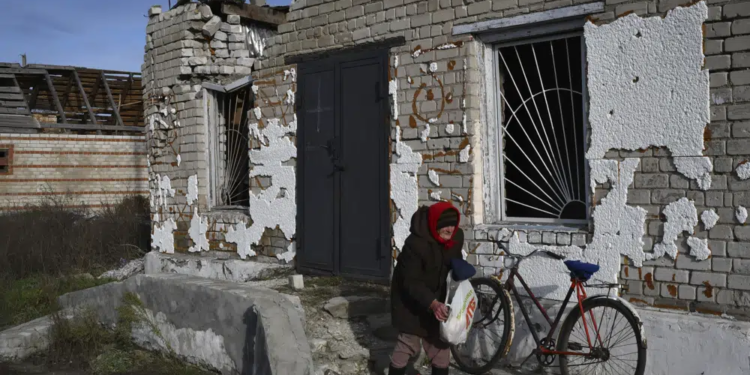 An elderly woman receives a food at a mobile humanitarian aid point in the village of Zarichne, Donetsk region, Ukraine, Friday, Dec. 2, 2022. (AP Photo/Andriy Andriyenko)