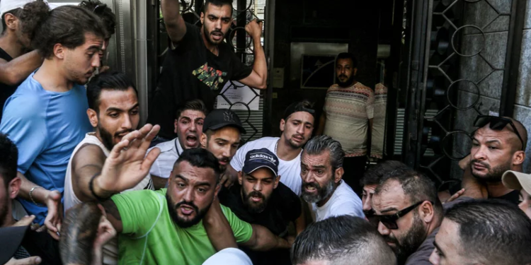 Lebanese activists gather outside a local bank in support of Abed Soubra, who stormed the branch demanding access to his own accounts, in Beirut on Sept 16. Lebanese police detained Soubra after he entered the bank and, armed with a gun, demanded access to his deposits. It was the third such incident in Lebanon that week alone. Marwan Naamani/Picture Alliance/Getty Images