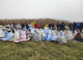 Rescued migrants sit covered in blankets at a beach near Cutro, southern Italy, Sunday, Feb. 26, 2023. Rescue officials say an undetermined number of migrants have died and dozens have been rescued after their boat broke apart off southern Italy. (Antonino Durso/LaPresse via AP)
