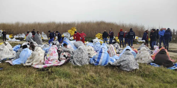 Rescued migrants sit covered in blankets at a beach near Cutro, southern Italy, Sunday, Feb. 26, 2023. Rescue officials say an undetermined number of migrants have died and dozens have been rescued after their boat broke apart off southern Italy. (Antonino Durso/LaPresse via AP)