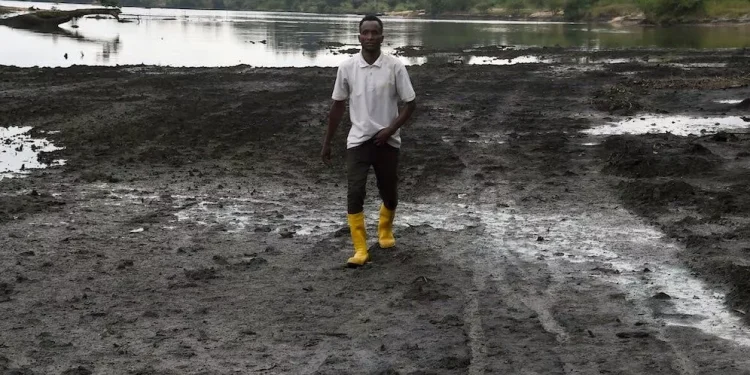 A farmer walks on a marshy shore of a river polluted by oil spills at B-Dere, Ogoniland in Rivers State, Nigeria on Aug. 23, 2021. PIUS UTOMI EKPEI / AFP via Getty Images